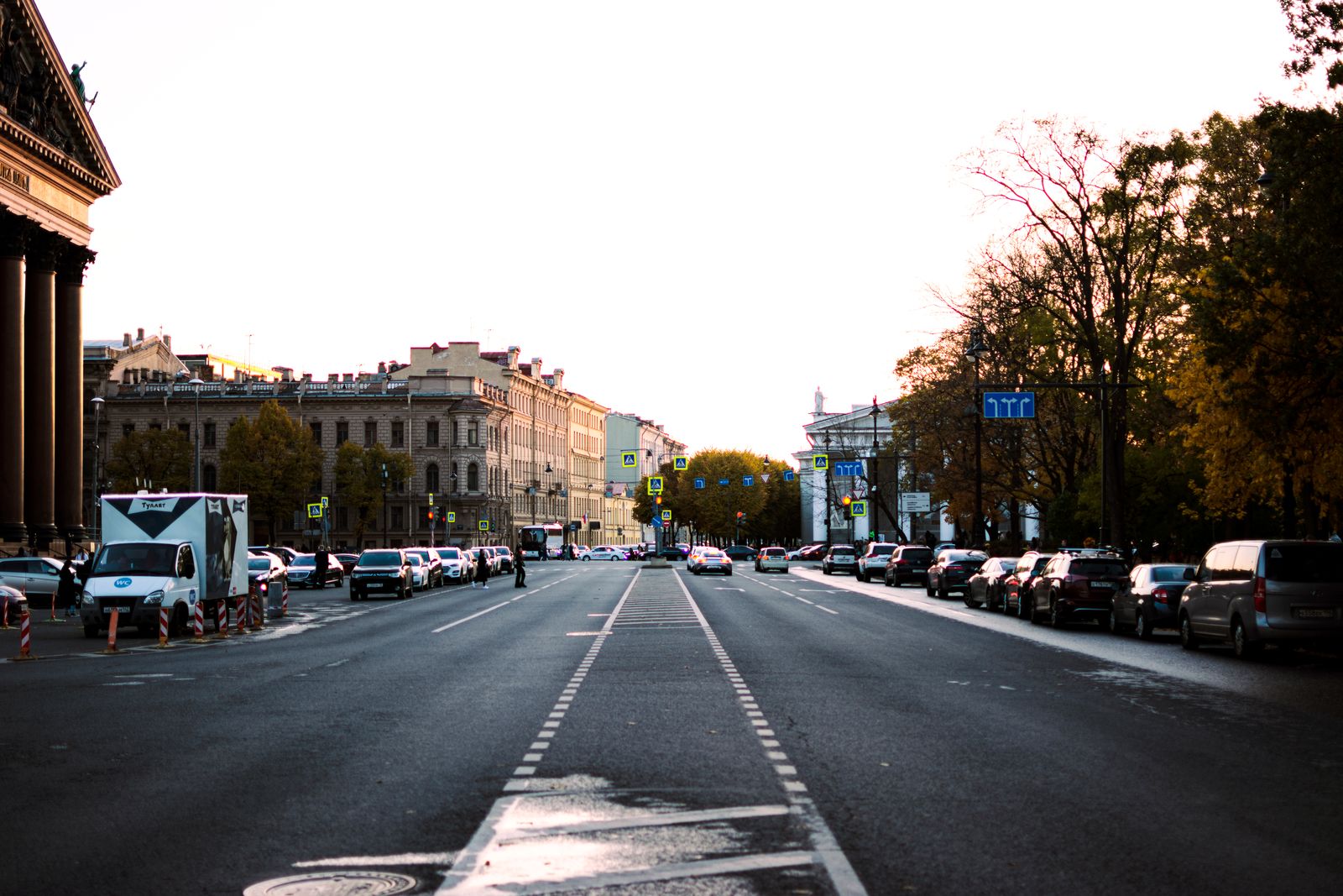 A bustling city street lined with cars at sunset, capturing urban life.